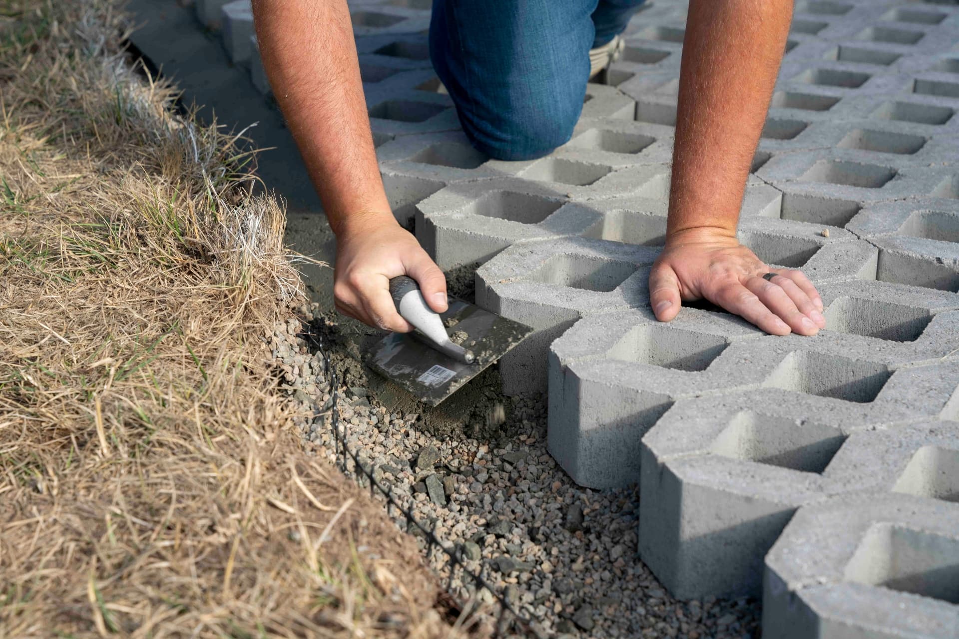 Skilled hands laying concrete pavers representing craftsmanship and hard work